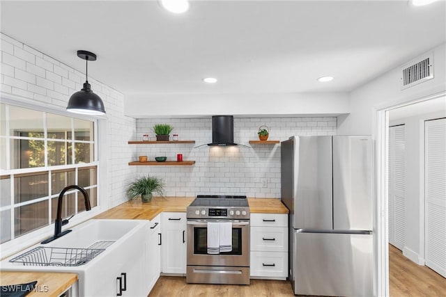 kitchen with wood counters, visible vents, appliances with stainless steel finishes, wall chimney range hood, and open shelves