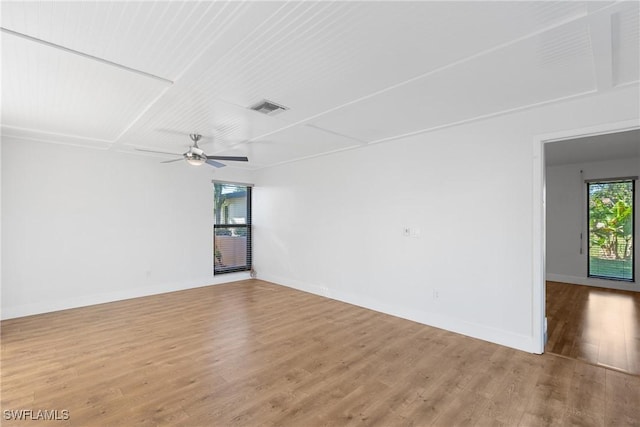 unfurnished room with a ceiling fan, wood finished floors, visible vents, and baseboards