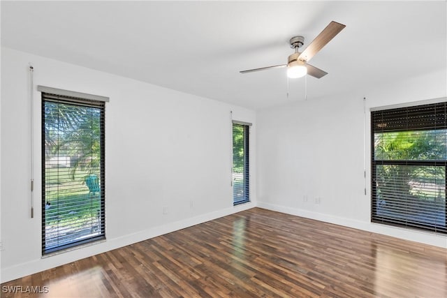 empty room with wood finished floors, a ceiling fan, and baseboards