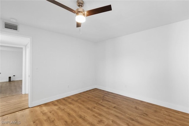 empty room with a ceiling fan, light wood-type flooring, visible vents, and baseboards