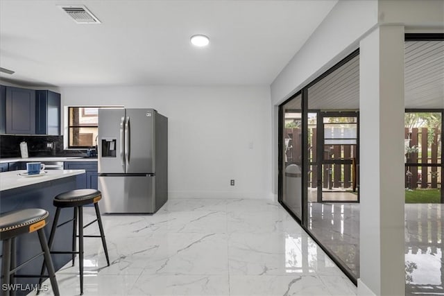 1212 SE 6th Ter Unit 83, Cape Coral, FL 33990 - kitchen with stainless steel fridge, light marble finish flooring, light countertops, a breakfast bar area, and baseboards