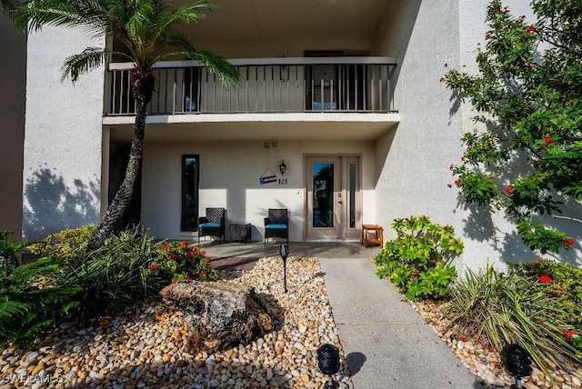 property entrance featuring a balcony and stucco siding