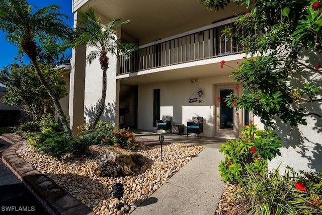 exterior space with a balcony, a patio area, and stucco siding