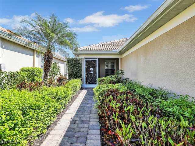 doorway to property with a tile roof and stucco siding