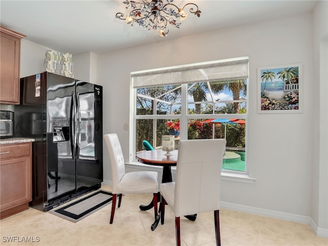 dining room featuring light tile patterned floors, a notable chandelier, and baseboards