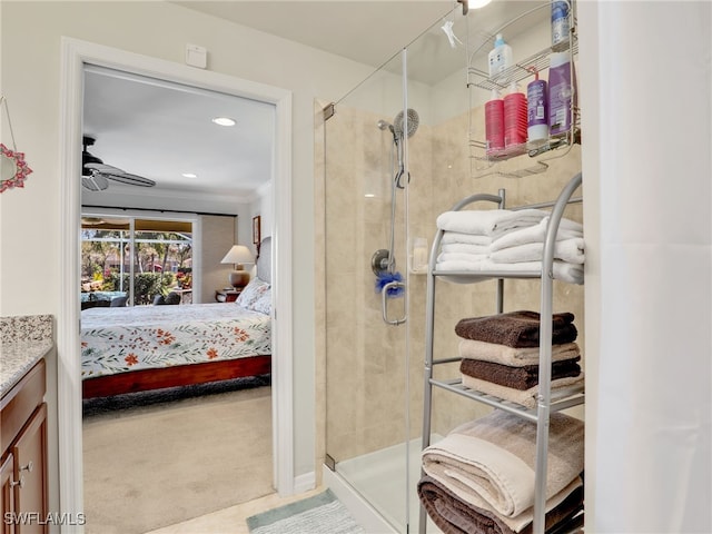 ensuite bathroom with a ceiling fan, a stall shower, ornamental molding, vanity, and ensuite bath