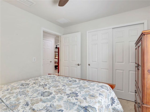 bedroom featuring ceiling fan, a closet, visible vents, and light colored carpet