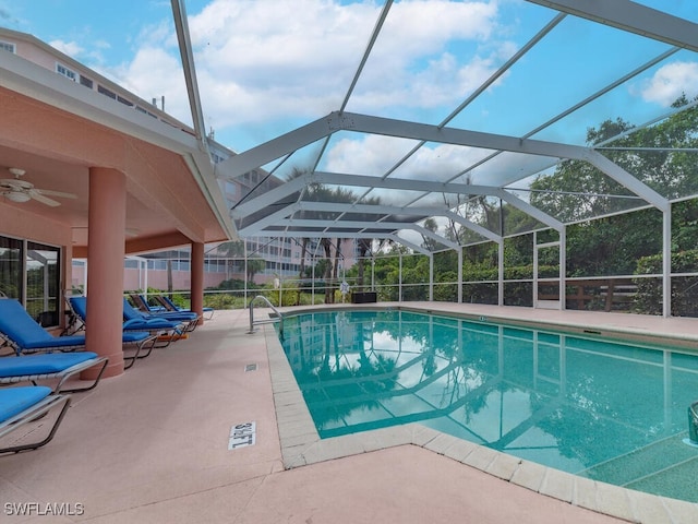 outdoor pool with glass enclosure, a patio, and a ceiling fan