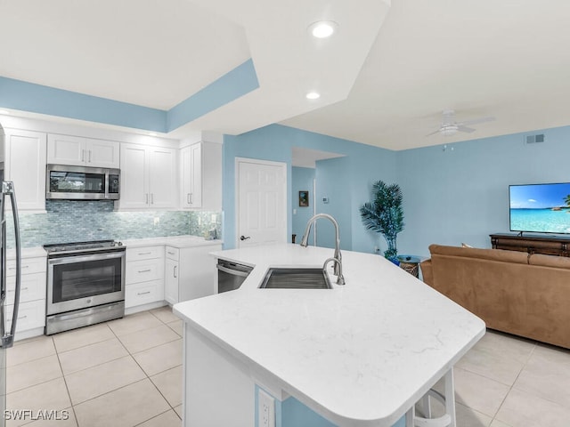 kitchen with stainless steel appliances, visible vents, open floor plan, a kitchen island with sink, and a sink