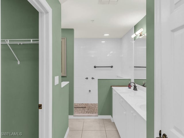 full bathroom featuring double vanity, tile patterned flooring, a walk in closet, a walk in shower, and a sink