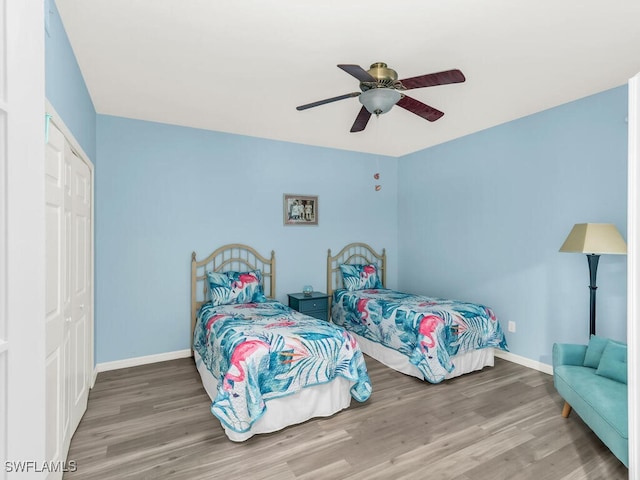 bedroom with a ceiling fan, a closet, baseboards, and wood finished floors