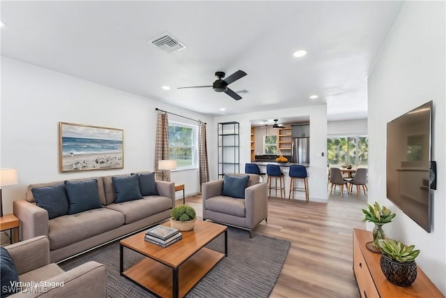 living room featuring light wood-type flooring, visible vents, a ceiling fan, and recessed lighting