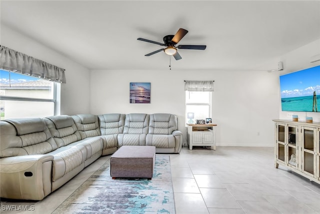 living area with a ceiling fan, baseboards, and light tile patterned floors