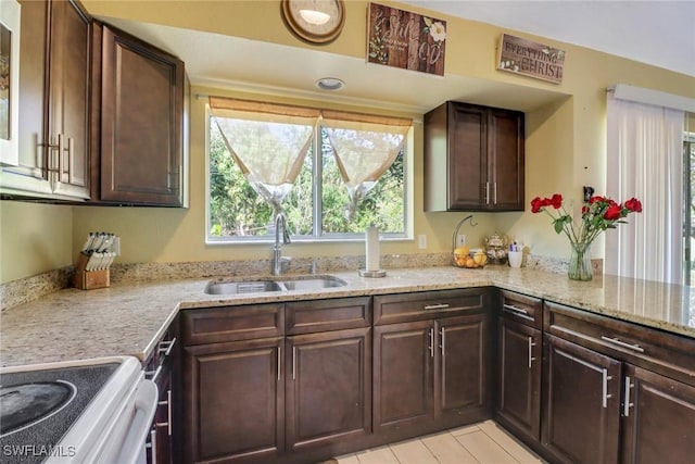 kitchen featuring dark brown cabinets, electric range, a sink, and light stone countertops