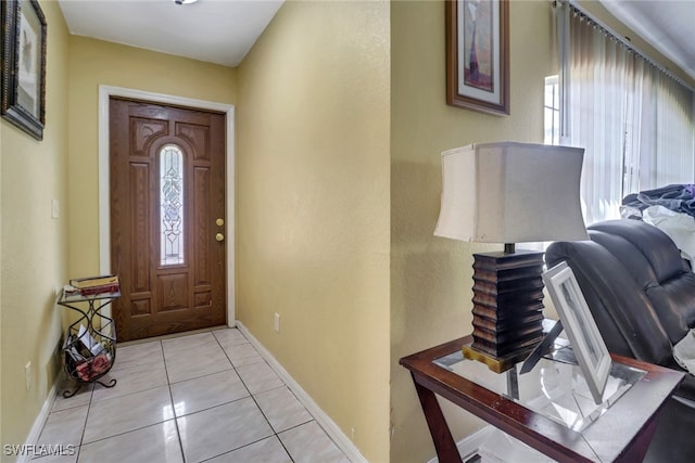 foyer entrance with light tile patterned floors, baseboards, and a wealth of natural light