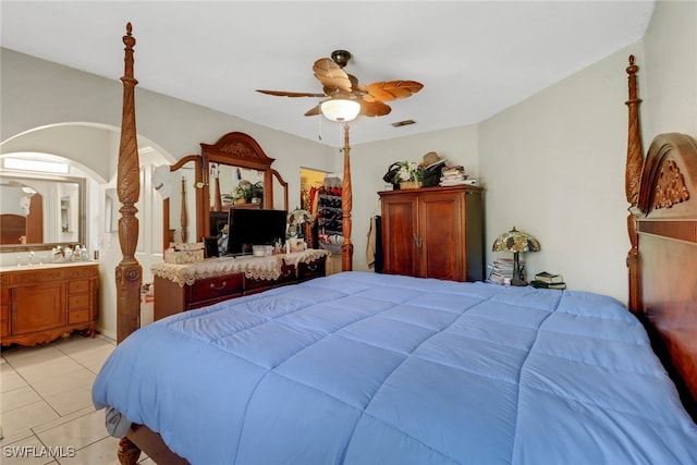 bedroom featuring light tile patterned floors, ceiling fan, a sink, and ensuite bathroom