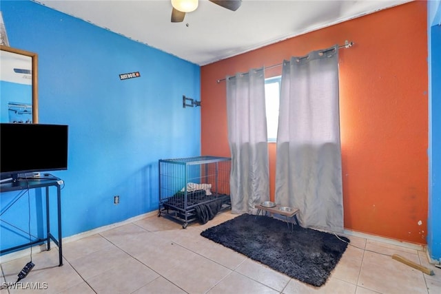 interior space with a ceiling fan, light tile patterned flooring, and baseboards