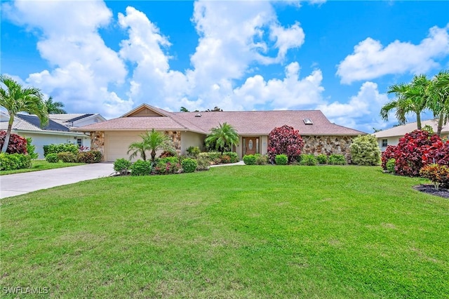 ranch-style home with stone siding, a front yard, concrete driveway, and an attached garage