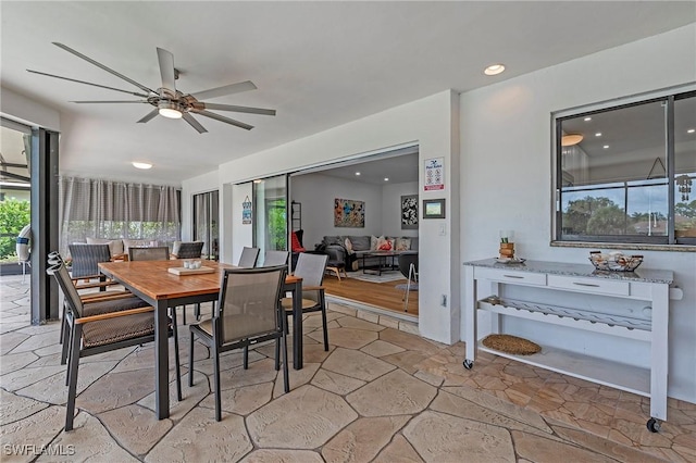 dining room featuring stone tile floors, a ceiling fan, a wealth of natural light, and recessed lighting