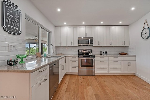 kitchen with light wood-type flooring, white cabinetry, stainless steel appliances, and a sink