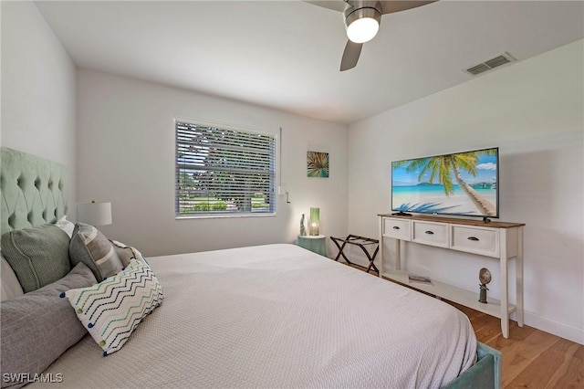 bedroom with ceiling fan, wood finished floors, visible vents, and baseboards