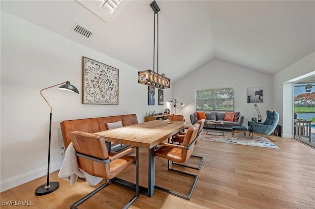 dining space with lofted ceiling, light wood-type flooring, visible vents, and baseboards