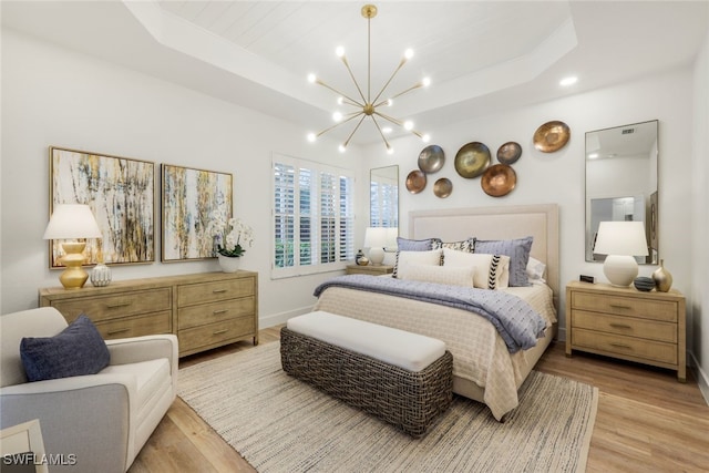 bedroom featuring light wood-type flooring, baseboards, a tray ceiling, and a notable chandelier