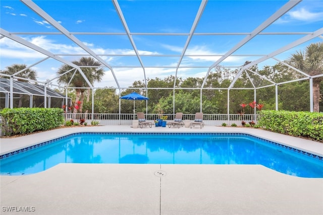 pool featuring glass enclosure, a patio area, and fence