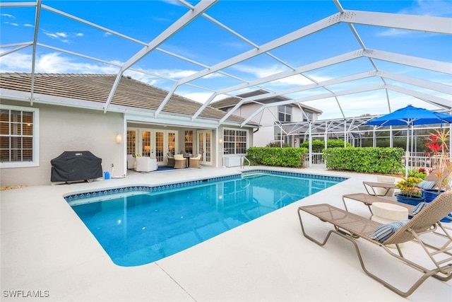 pool with a patio area, glass enclosure, a grill, and an outdoor hangout area