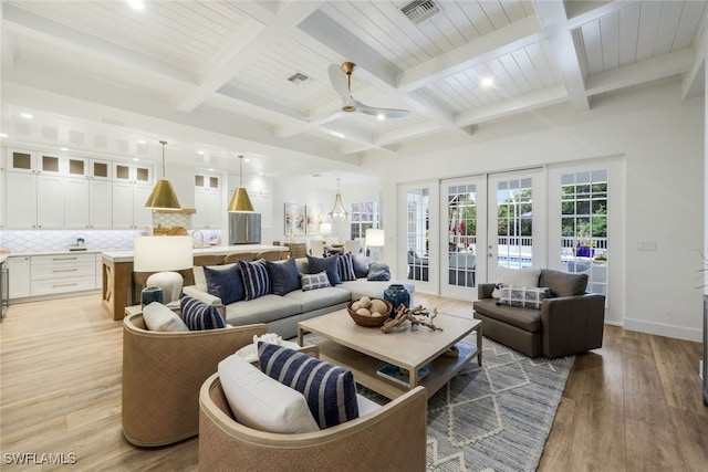 living room with baseboards, visible vents, beamed ceiling, french doors, and light wood-style floors