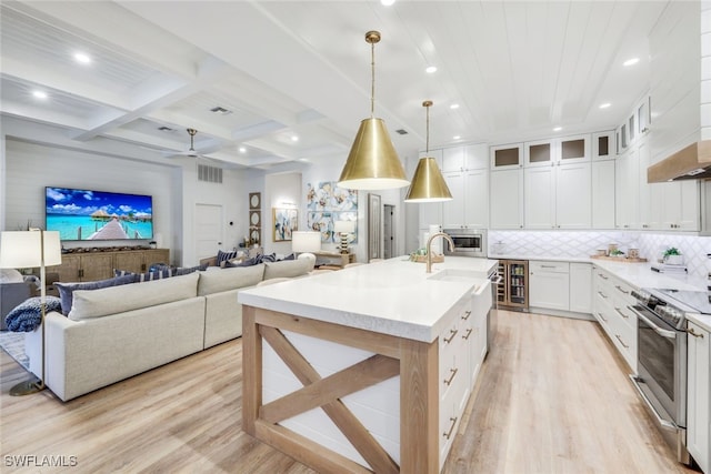 kitchen with open floor plan, light countertops, appliances with stainless steel finishes, and glass insert cabinets