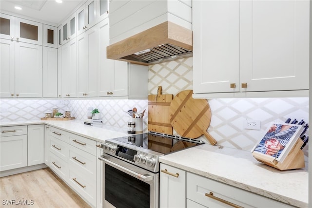 kitchen featuring glass insert cabinets, electric stove, premium range hood, and white cabinets