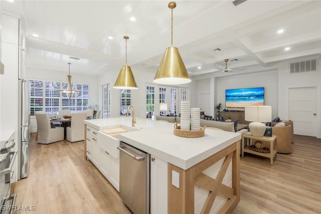 kitchen featuring a center island with sink, light countertops, open floor plan, white cabinetry, and dishwasher