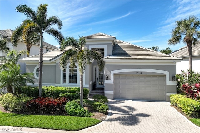 view of front of property featuring a garage, a tiled roof, decorative driveway, and stucco siding