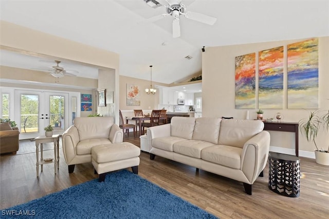 living area with ceiling fan with notable chandelier, lofted ceiling, and wood finished floors