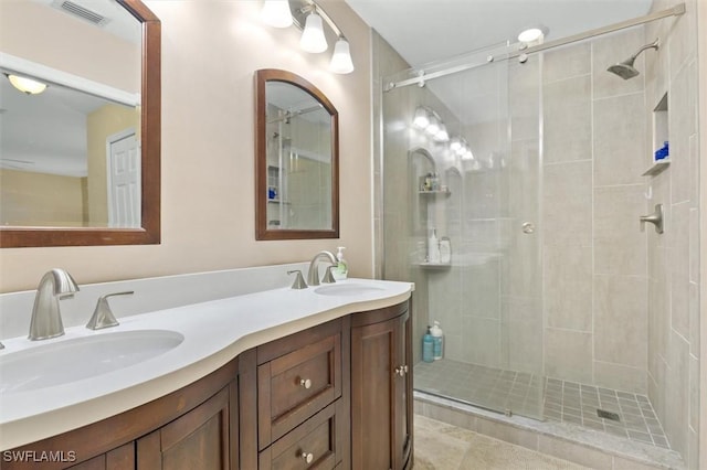 bathroom with double vanity, a stall shower, a sink, and visible vents