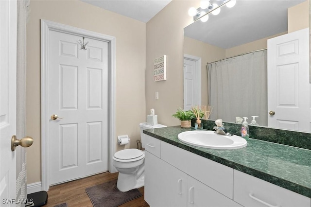 bathroom with toilet, wood finished floors, and vanity