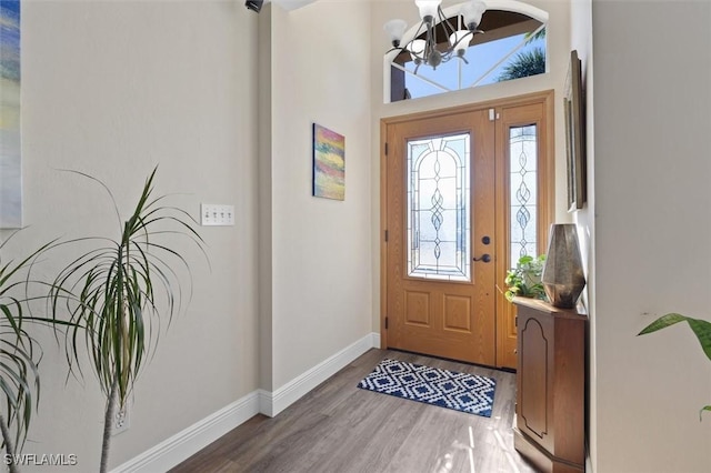 foyer entrance featuring baseboards, a chandelier, and wood finished floors