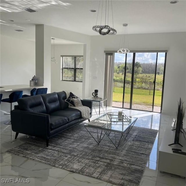 living area featuring marble finish floor, visible vents, and a chandelier