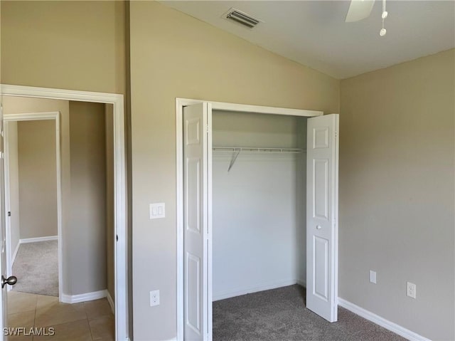 unfurnished bedroom with tile patterned flooring, carpet floors, visible vents, baseboards, and a closet