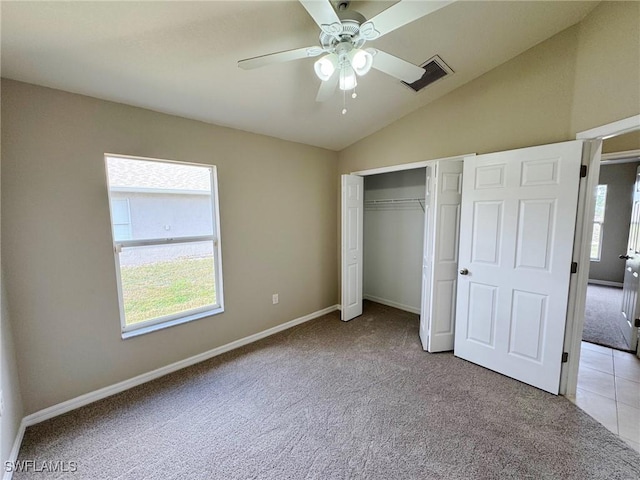 unfurnished bedroom featuring baseboards, visible vents, light colored carpet, lofted ceiling, and a closet