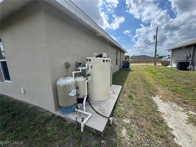 view of side of home featuring a yard, stucco siding, and central air condition unit