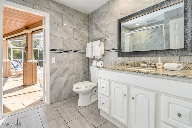 bathroom featuring toilet, a stall shower, tile walls, and vanity