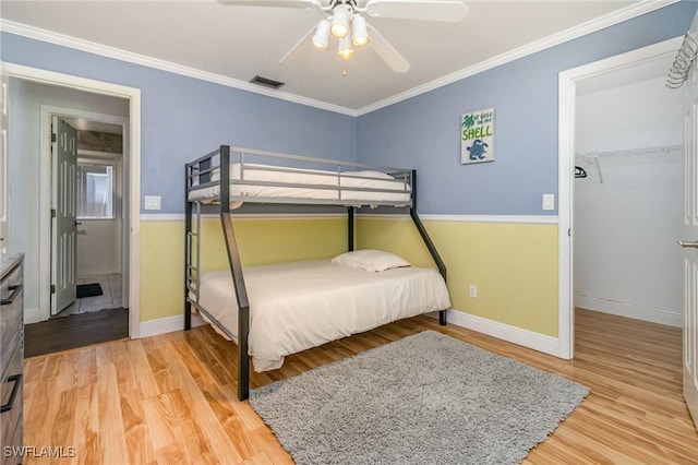 bedroom with light wood-style floors, visible vents, crown molding, and baseboards