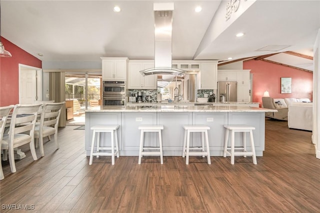 kitchen featuring island range hood, lofted ceiling with beams, stainless steel appliances, a kitchen bar, and separate washer and dryer