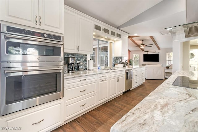 kitchen featuring appliances with stainless steel finishes, open floor plan, white cabinets, and vaulted ceiling