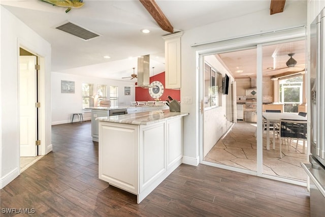 kitchen featuring light stone counters, white cabinets, visible vents, and a peninsula