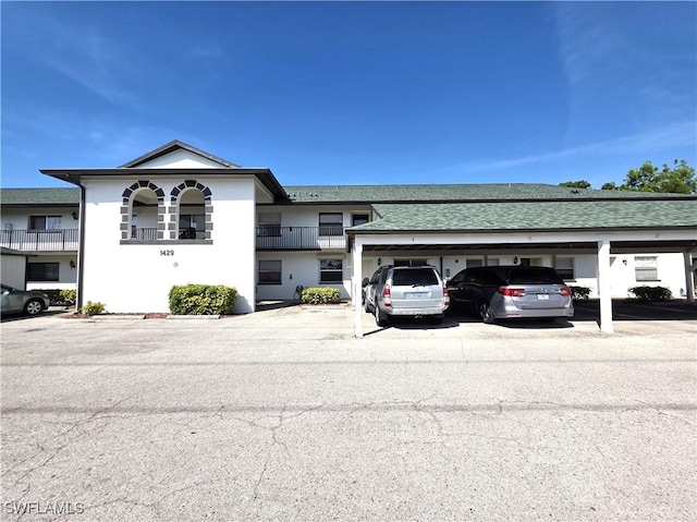 view of property with covered parking and roof with shingles