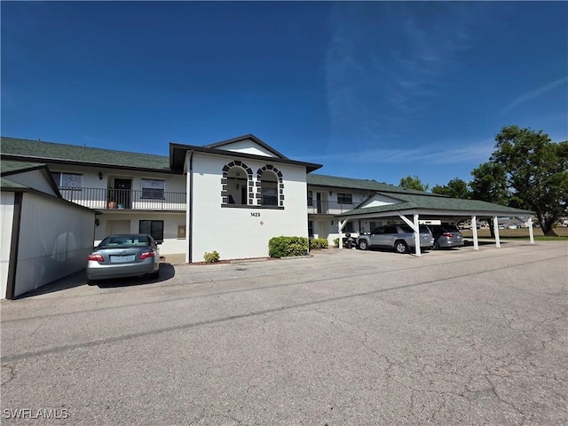 exterior space featuring stucco siding and covered and uncovered parking