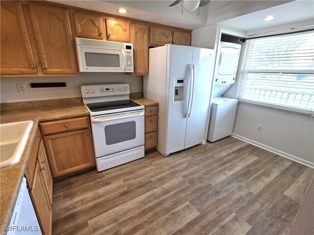 kitchen with stacked washer and dryer, white appliances, dark wood-style flooring, a sink, and light countertops